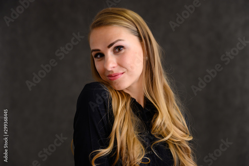 Close-up portrait of a pretty blonde girl with long curly hair standing in the studio on a gray background with emotions in different poses. Beauty, Model, Cosmetics