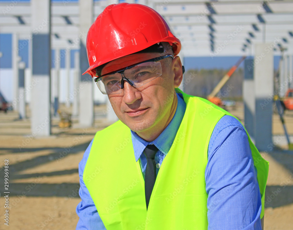 Portrait of construction manager with safety glasses and work vest. He is satisfied with his job, looks at the camera, businessman concept Portrait of construction manager with safety glasses and work vest. He is satisfied with his job, looks at the camera, businessman concept