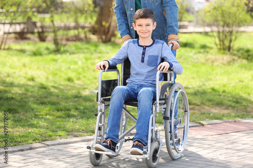 Preteen boy in wheelchair with his father at park on sunny day