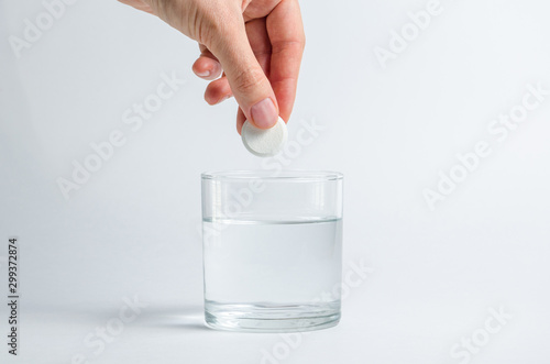 A hand holding effervescent soluble calcium tablet or vitamin C is placed in a glass of water. Health.The concept of a healthy lifestyle, prevention of vitamin deficiency. Isolated on white background