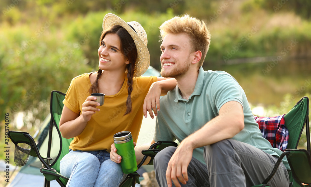 Obraz premium Young couple with hot drinks resting outdoors. Camping vacation