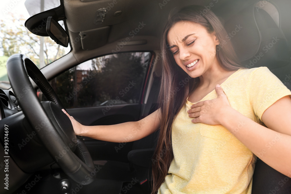 Young woman suffering from heart attack in car Young woman suffering from heart attack in car