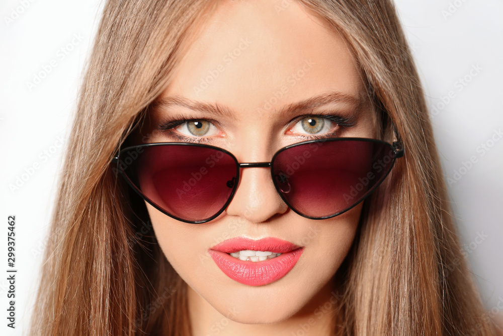 Young woman wearing stylish sunglasses on light background Young woman wearing stylish sunglasses on light background