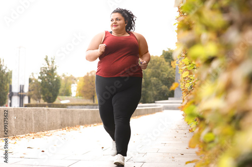Beautiful overweight woman running in park. Fitness lifestyle