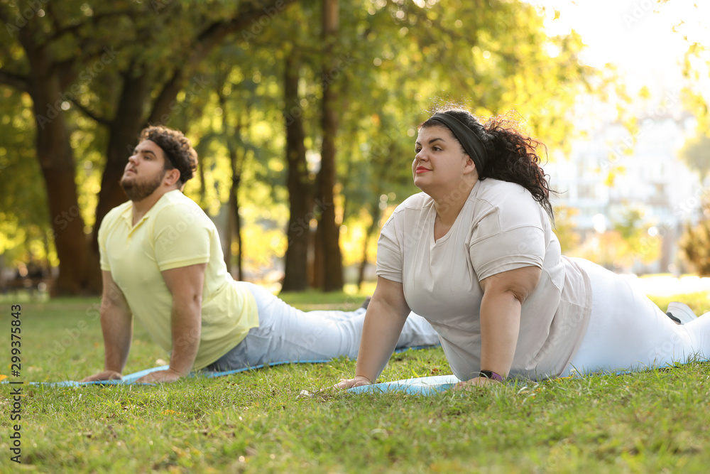 Overweight couple training together in park on sunny day Overweight couple training together in park on sunny day