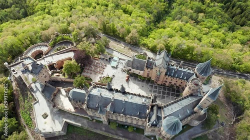 Aerial panorama of Burg Hohenzollern (Hohenzollern castle) with hills and villages surrounded by forests with beautiful foliage