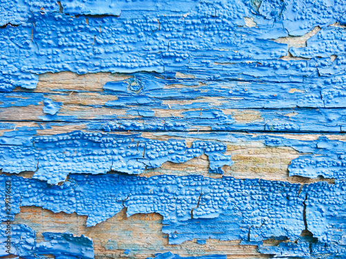 Wood texture with blue flaked paint. Peeling paint on weathered wood. Old cracked paint pattern on rusty background. Chapped paint on an old wooden surface