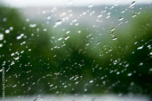 Natural background Drops on both sides of the glass from the rain and from the fogging abstract view, raindrops against the blue glass and the blurred landscape of the gradient of blue and green