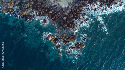 Aerial view of the coastal edge with waves, rocks and white foam