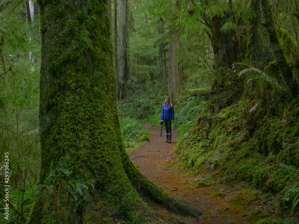 CLOSE UP: Cheerful young woman treks along a scenic trail in Hoh Rainforest.