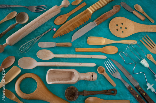 Many wooden spoons and rolling pin on the green background