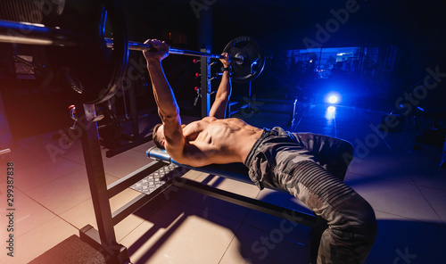 Fit young man lifting barbells doing workout at a gym. Sport, fitness, weightlifting, bodybuilding, training, athlete, workout exercises concept. View from the side. © Vadim