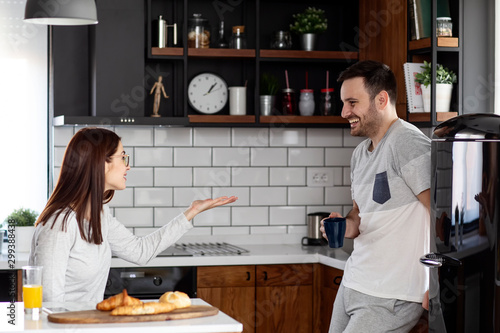 Couple in the kitchen eat breakfast with orange juice and pastry at table