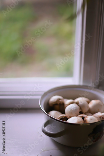 champignon mushrooms in an iron pan on a white windowsill. village concept