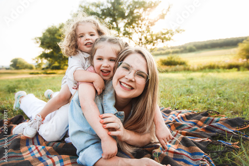 Blonde mother with two cute daughters are walking and having fun outdoors. Stylish, casual clothes.
