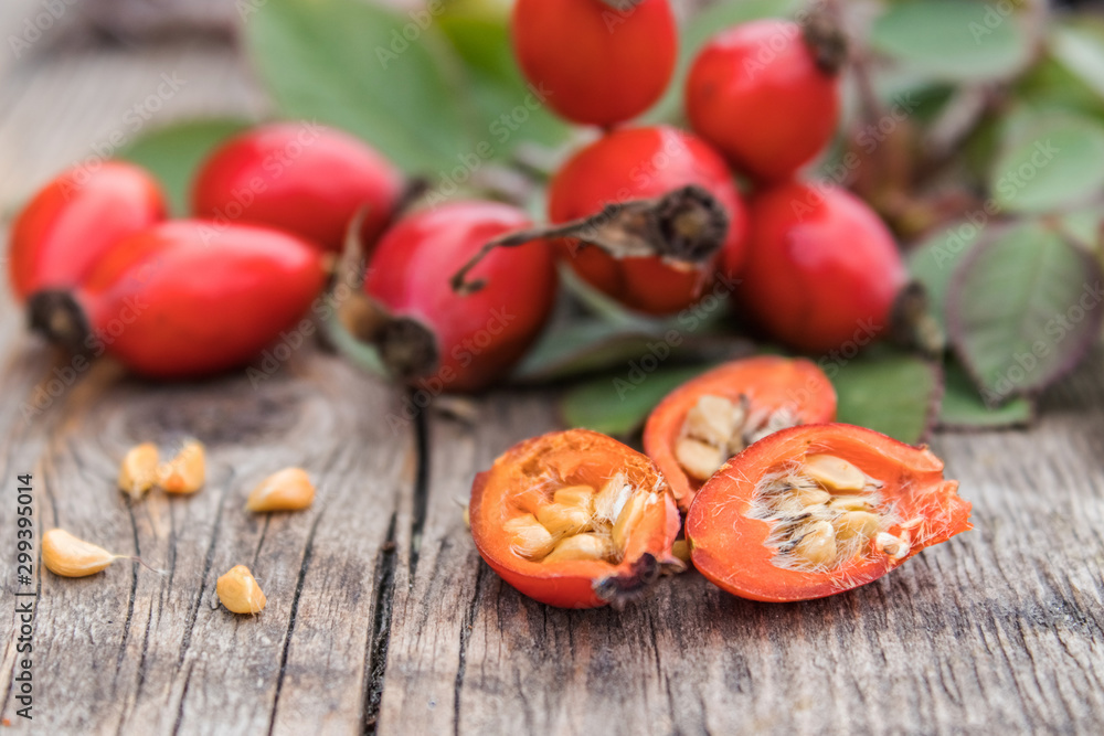 Red rose hips and ripened berries in half with seeds on old wooden boards. Red rose hips and ripened berries in half with seeds on old wooden boards.