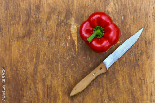 red Bulgarian sweet pepper-whole and cut into slices, chili pepper on a wooden Board, on a linen tablecloth in a colorful ornament,with a knife