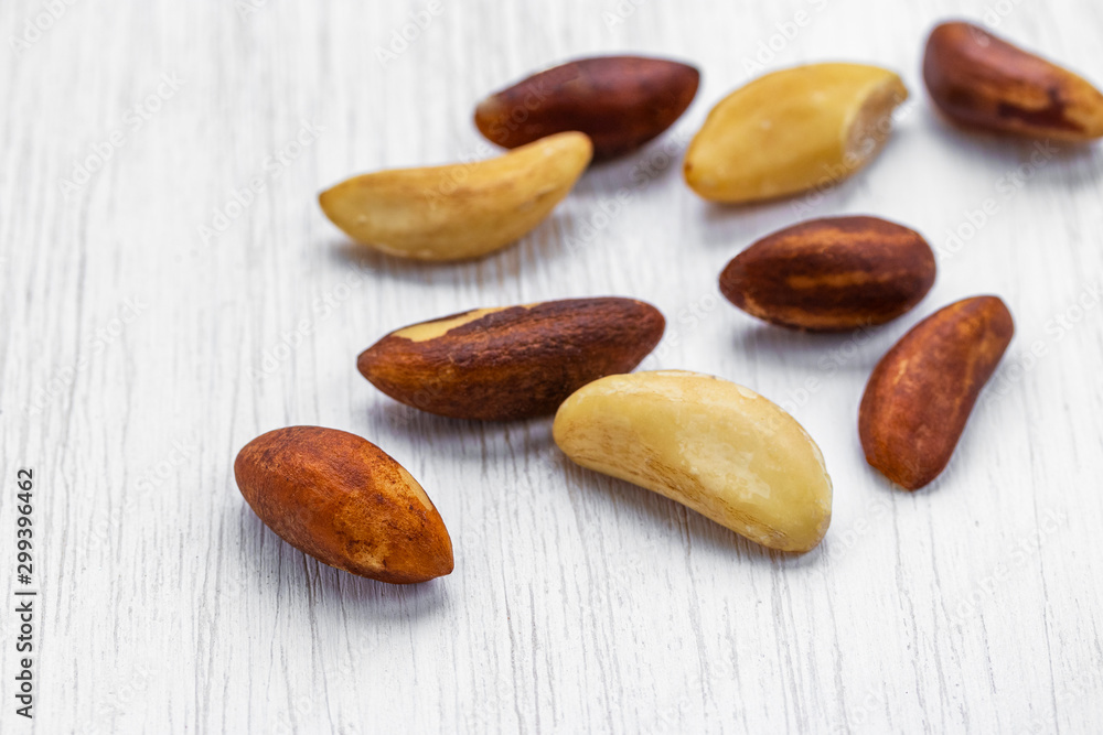 Unshelled brazil nuts lie on a white wooden surface, side view from above Unshelled brazil nuts lie on a white wooden surface, side view from above