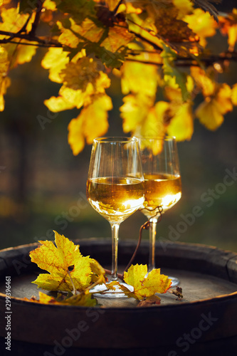 Two glasses of white wine on a wooden barrel at sunset