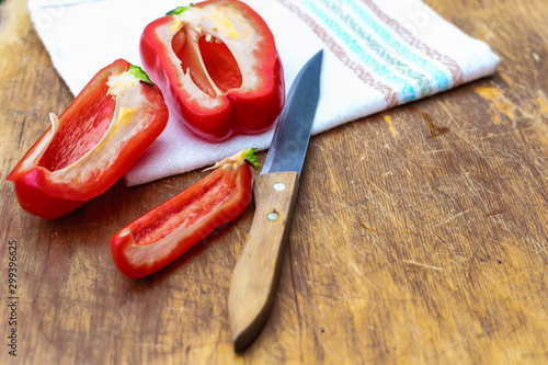 red Bulgarian sweet pepper-whole and cut into slices, chili pepper on a wooden Board, on a linen tablecloth in a colorful ornament,with a knife