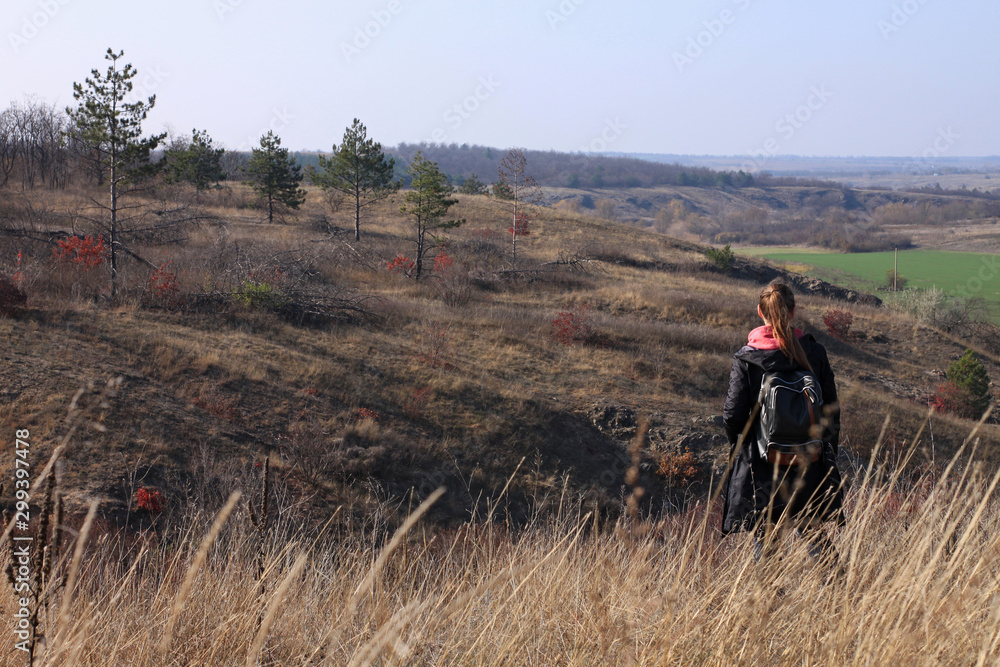 A young woman stays on a hill above the wild river and photographs the landscape. Solo travelling.