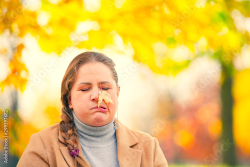 People, season and style concept - beautiful plus size woman grimacing in autumn park. Portrait of a sullen, frustrated blonde woman. Copy space