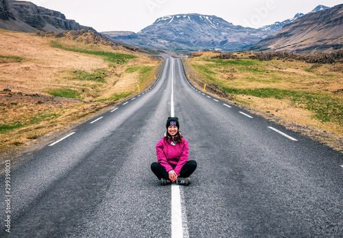 smiling girl sits in the middle of the empty road