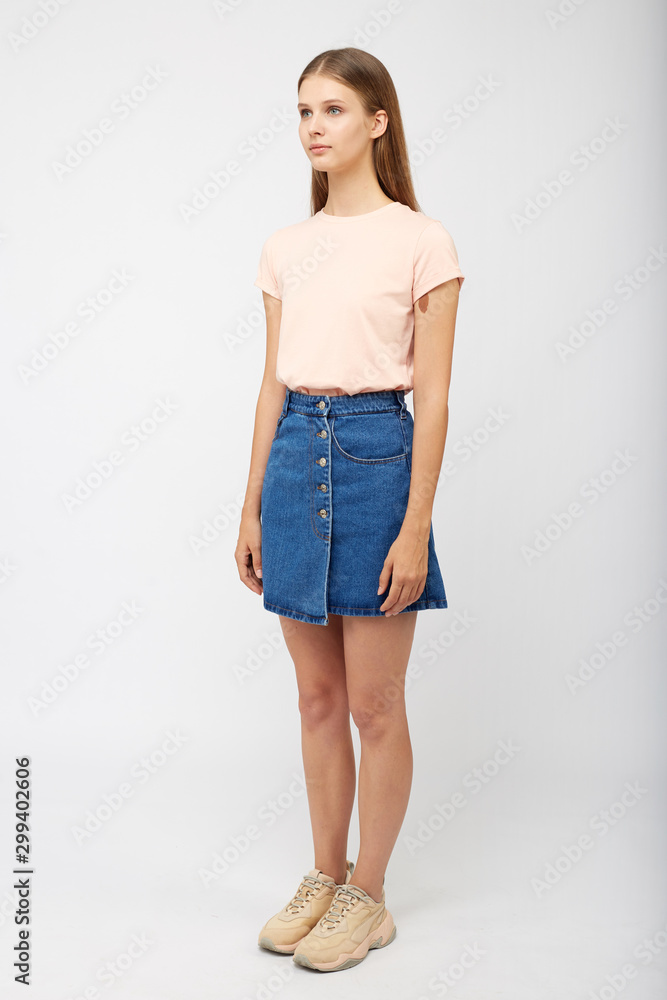 Teenager girl in a denim blue skirt on a white background. Teenager girl in a denim blue skirt on a white background.