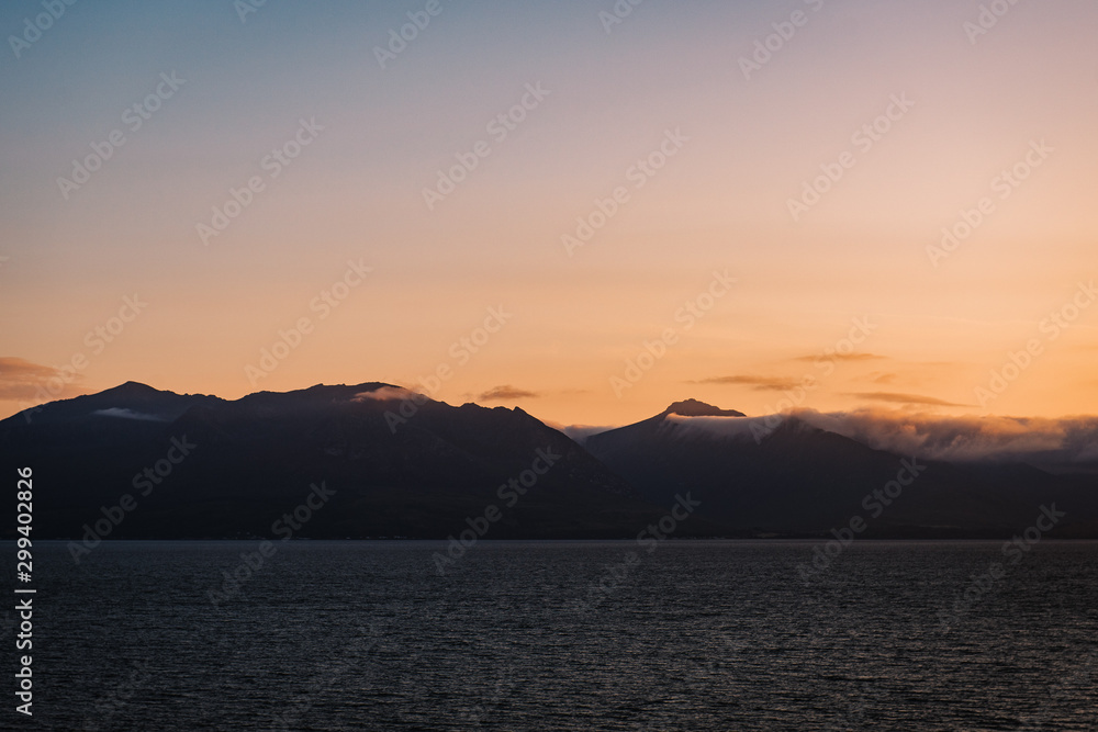 Sunset over the mountains, the ocean in the foreground