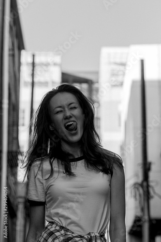 Woman with long hair on the street. Black and white portrait. Brick wall behind model. Street style fashion outfit. Urban lifestyle outfit. Plaid shirt, white t-shirt. Rebel girl. Different emotions.