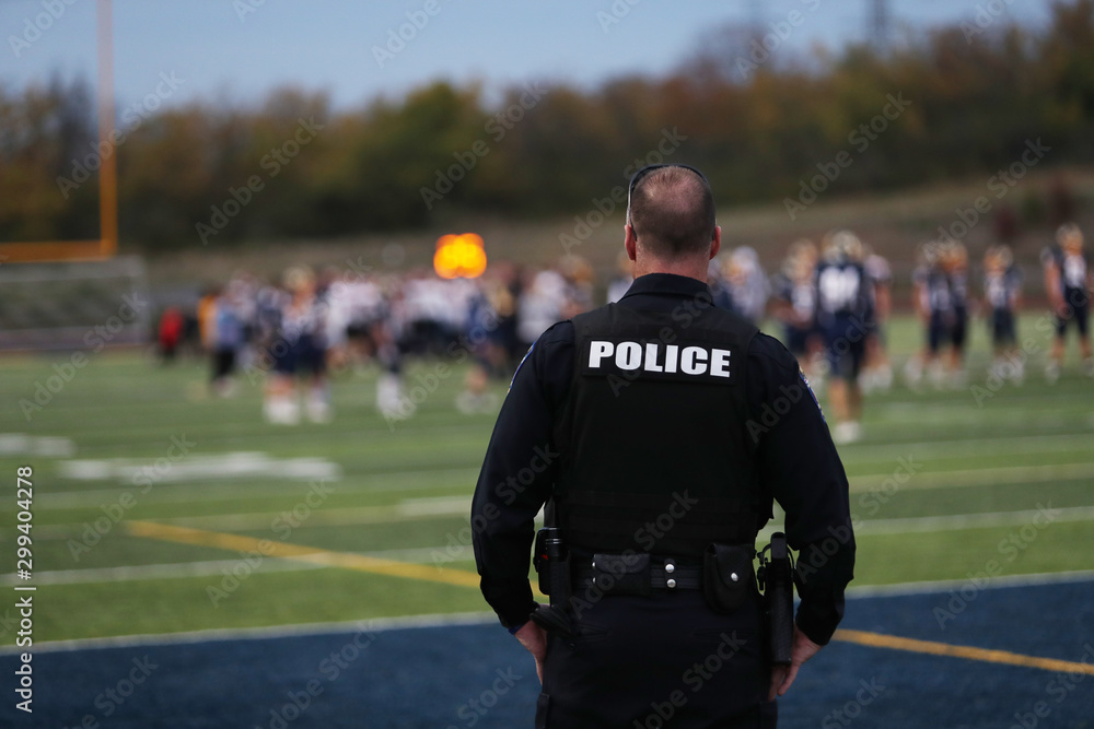 A local police officer works during a high school football game. A local police officer works during a high school football game.