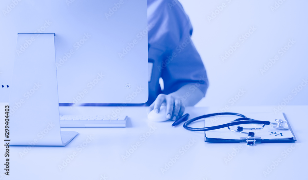 Unknown doctor woman filling up medical form while sitting at the desk in hospital office Unknown doctor woman filling up medical form while sitting at the desk in hospital office