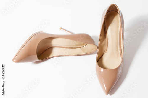 Closeup fashion high heels women shoes beige color isolated on white background. Top view. Stiletto shoe style in ladies wardrobe. High fashion and formal female accessory. Copy space. Selective focus
