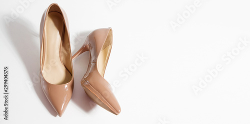 Closeup fashion high heels women shoes beige color isolated on white background. Top view. Stiletto shoe style in ladies wardrobe. High fashion and formal female accessory. Banner. Selective focus