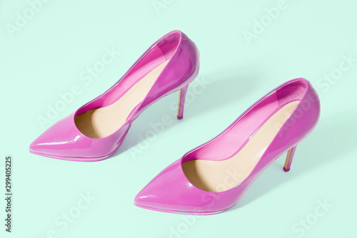 Closeup pink women patent leather shoes isolated on green background. Stilettos shoe type. Summer fashion and shopping concept. Luxury and glamour party ladies wardrobe accessory. Selective focus