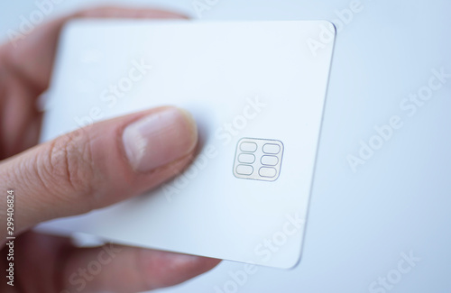 White plastic credit or debit card with chip in female fingers on white background. photo