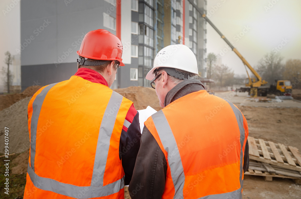 An engineer with a hard hat and helmet discussing a project at a construction site with a team leader. architecture construction concept. Industrial safety An engineer with a hard hat and helmet discussing a project at a construction site with a team leader. architecture construction concept. Industrial safety