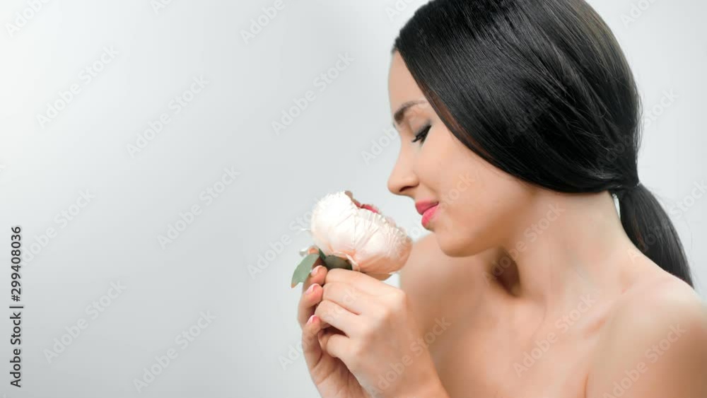 Pleasant seductive young brunette girl smiling holding beauty flower at white studio background Pleasant seductive young brunette girl smiling holding beauty flower at white studio background