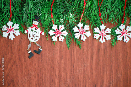 Green spruce branches. Brown wooden background. White, red, multi-colored Christmas toys. Decorations for Christmas tree made of wood and ceramics. Festive fun concept. Congratulatory backdrop. 