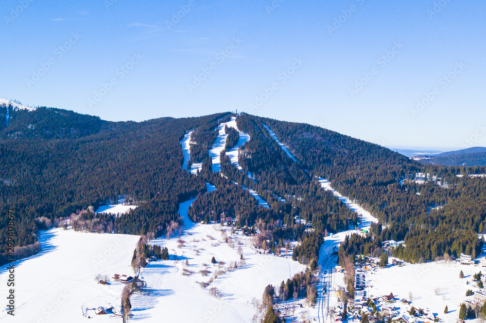 Aerial view of Spicak mountain with ski slopes near Zelezna Ruda. Winter resort in national park Sumava, Czech republic, European union.
