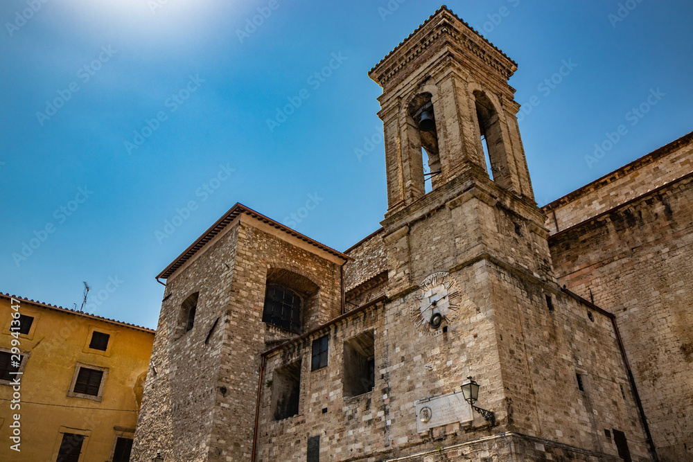 Narni, Umbria, Italy - The medieval cathedral of San Giovenaleo in the ancient village of Narni. The side with the bell tower and the church clock. The blue sky in the summer.