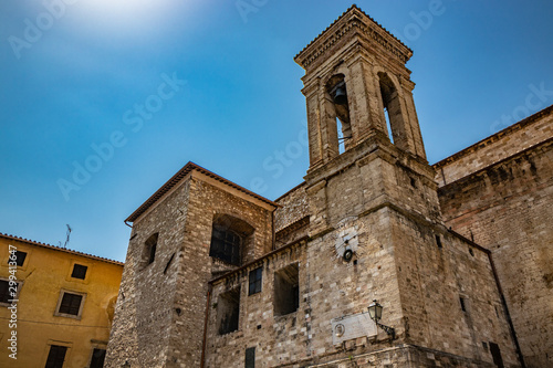 Fototapeta Naklejka Na Ścianę i Meble -  Narni, Umbria, Italy - The medieval cathedral of San Giovenaleo in the ancient village of Narni. The side with the bell tower and the church clock. The blue sky in the summer.
