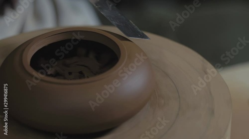 the master potter processes the teapot from Yixing clay with a metal spatula on a wooden shaft. Handmade clay teapot for tea ceremony. brown pottery teapot. 4k video. 59.94 fps