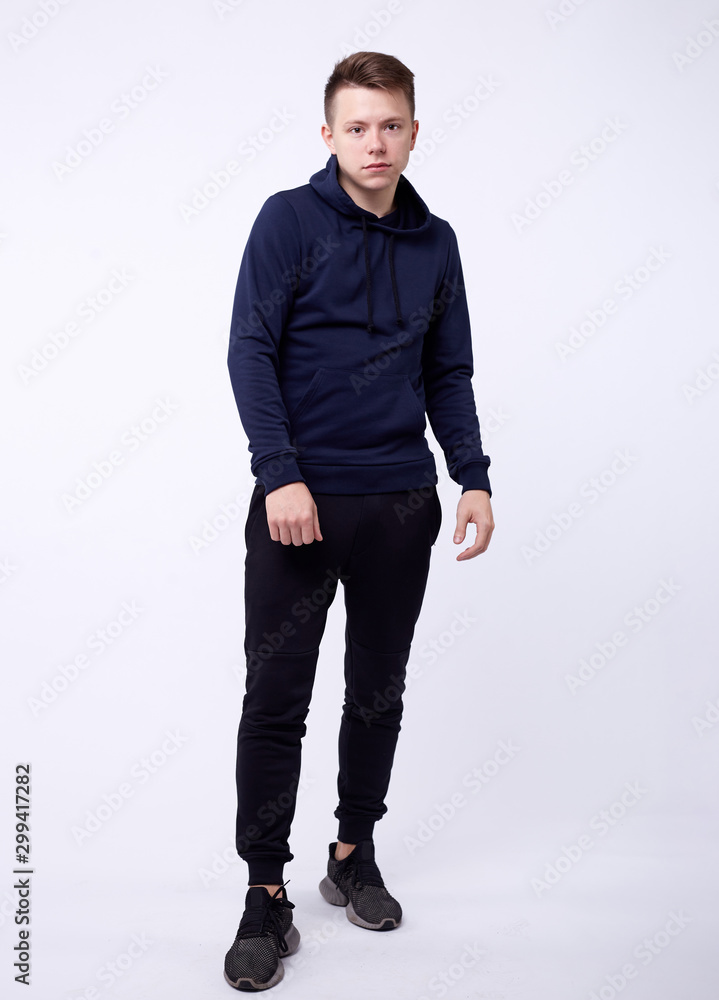 Isolated portrait of handsome serious young man in black hoodie standing with his hands in pockets. Concept of hacking and fashion Isolated portrait of handsome serious young man in black hoodie standing with his hands in pockets. Concept of hacking and fashion