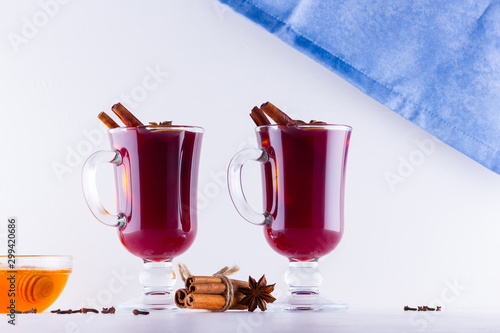 Glass of hot mulled wine with spices and honey on white background. Christmas mulled wine with orange, star anise and cinnamon. Two glasses of winter Christmas drink