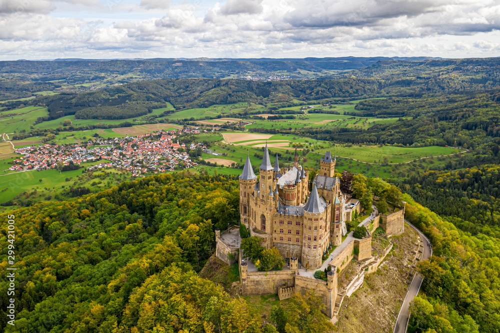 Aerial panorama of Burg Hohenzollern (Hohenzollern castle) with hills and villages surrounded by forests with beautiful foliage