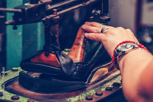 Worker in the handmade footwear industry, is fixing sole for shoes.