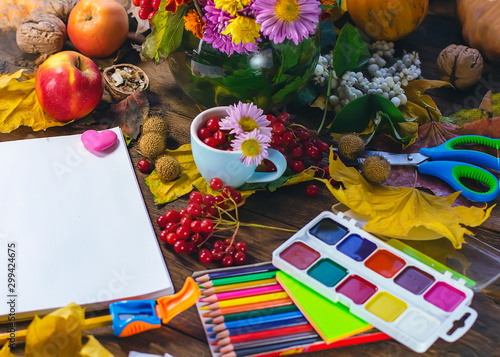 office and school stationery and notebook on a background of autumn leaves and chrysanthemums.
