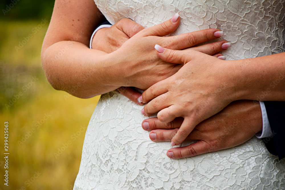 Close up on grooms hands holding on to his bride at outdoor wedding Close up on grooms hands holding on to his bride at outdoor wedding