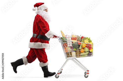 Fotografia, Obraz Santa Claus in a hurry, running and pushing a shopping cart with food